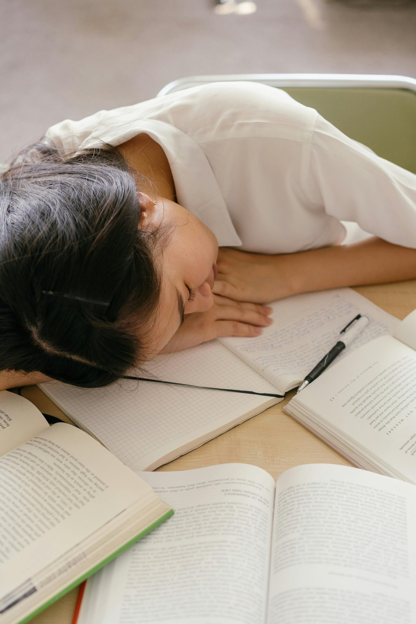 Exhausted student asleep on books illustrating academic burnout.